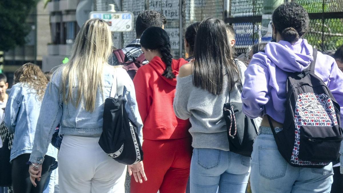 Varias personas jovenes caminan por la calle.
