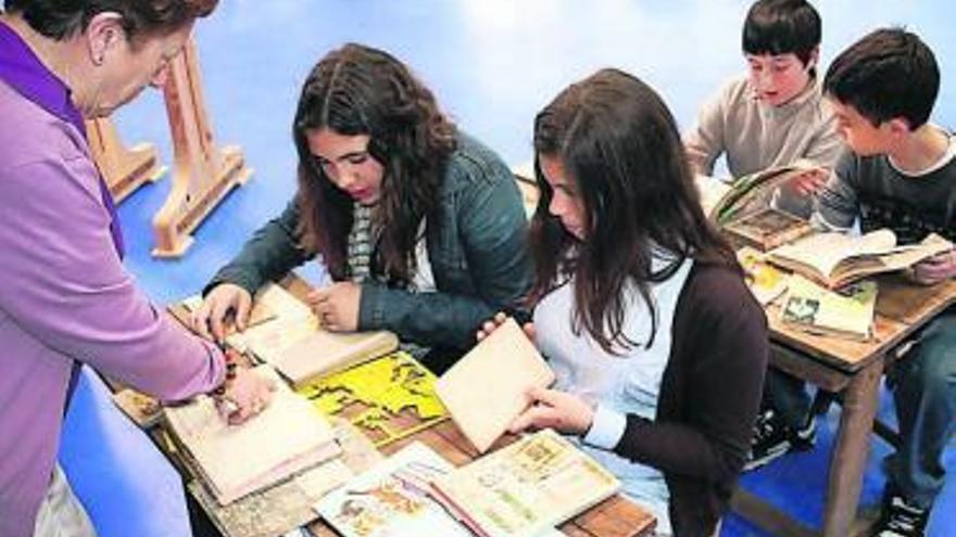 La maestra retirada Loli Valdés enseña a los alumnos los libros de antaño.