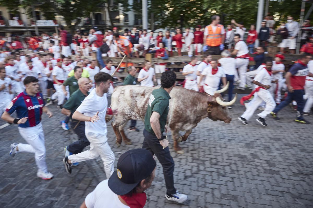 Varios corredores junto a un toro durante el segundo encierro de las Fiestas de San Fermín 2022, de la ganadería de Fuente Ymbro.