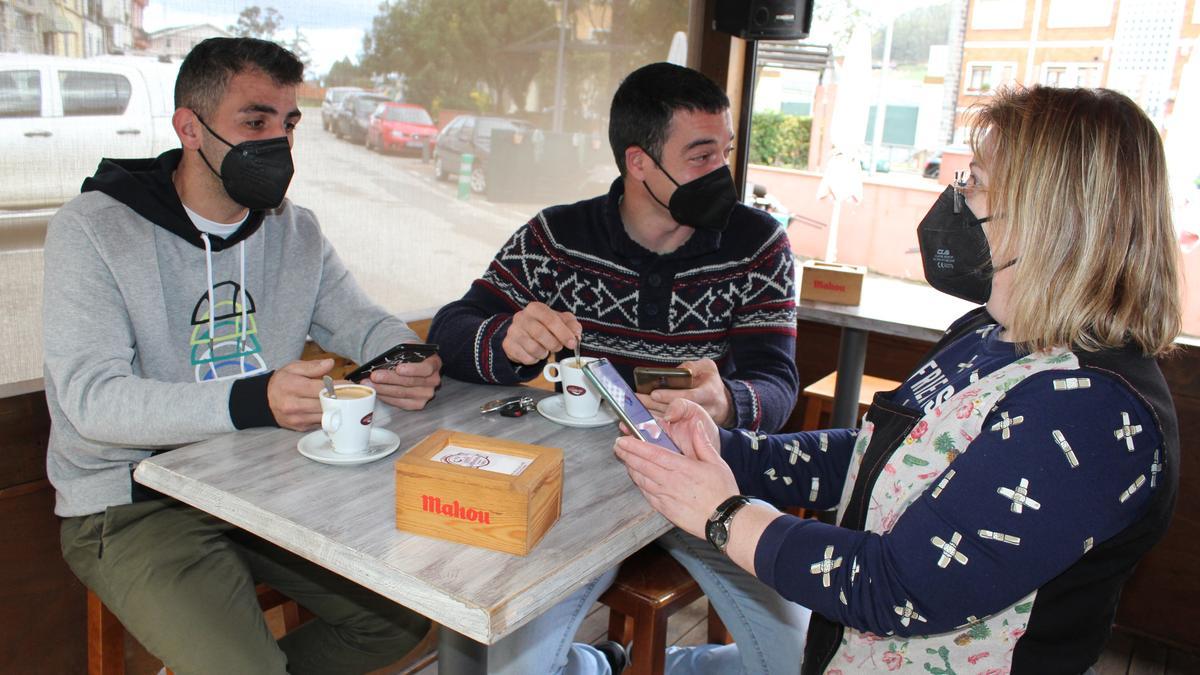 La hostelera Mónica Barrera pide a Pedro González y Alejandro García el pasaporte en el bar Casa Miranda, de Vegadeo