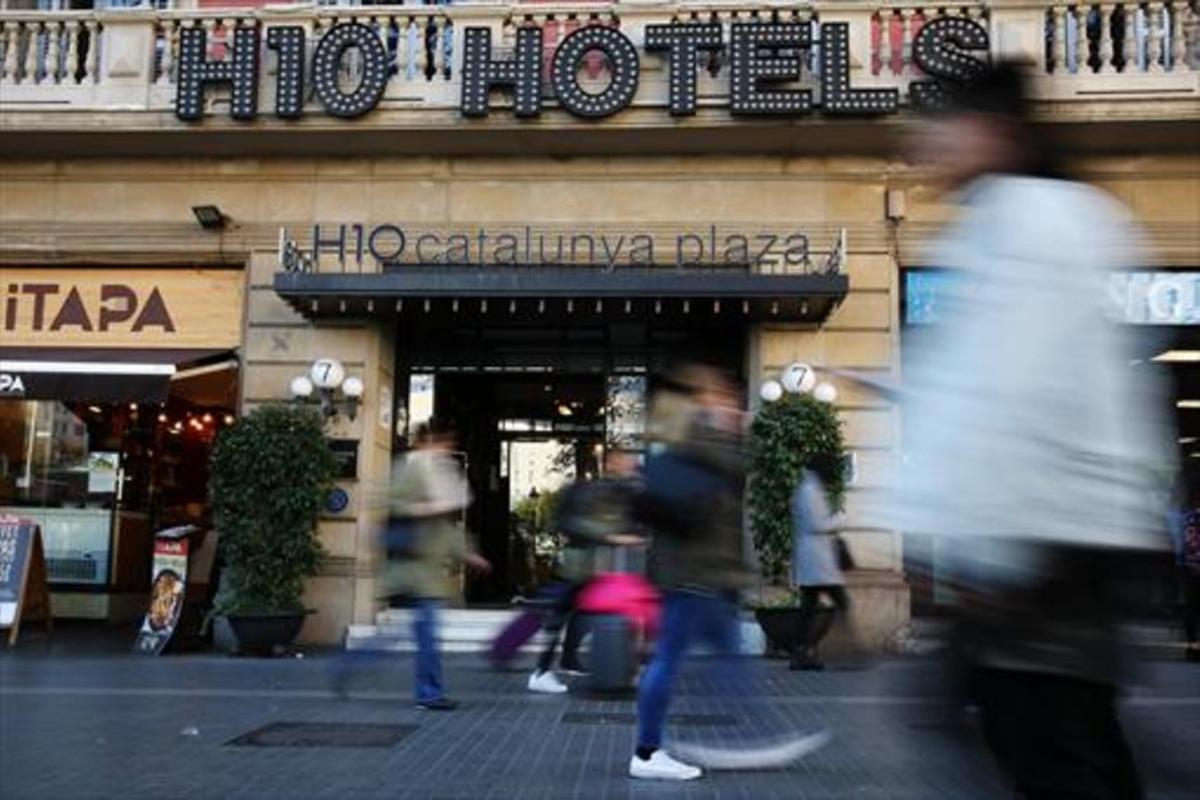 Turistas y transeúntes ante el Hotel H10 Catalunya Plaza, en la plaza de Catalunya de Barcelona.