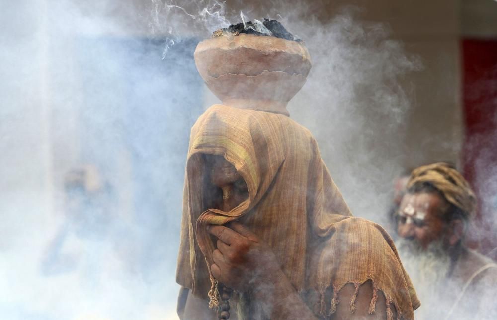 A Sadhu covers his face as an earthen pot with ...