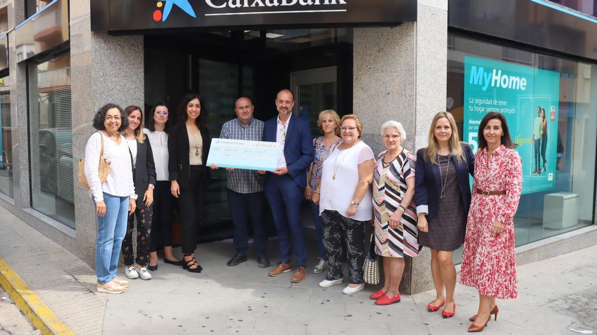 Voluntarias de Cáritas y el párroco reciben el cheque del director de CaixaBank.