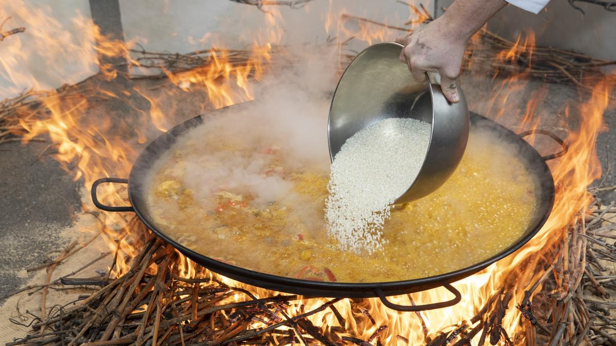 Un cocinero echa el arroz en una paella