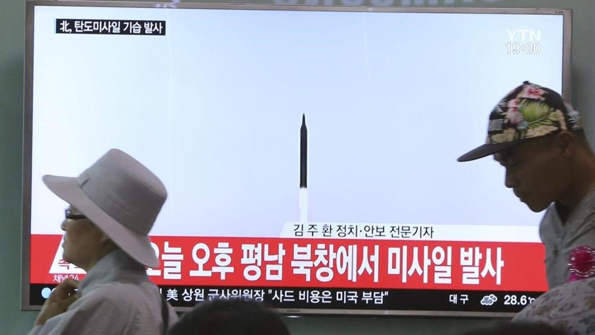 Dos personas pasan ante una pantalla de televisión donde se muestran imágenes de archivo de un lanzamiento de un misil por parte de Corea del Norte, en la estación ferroviaria de Seúl (Corea del Sur), el 21 de mayo.