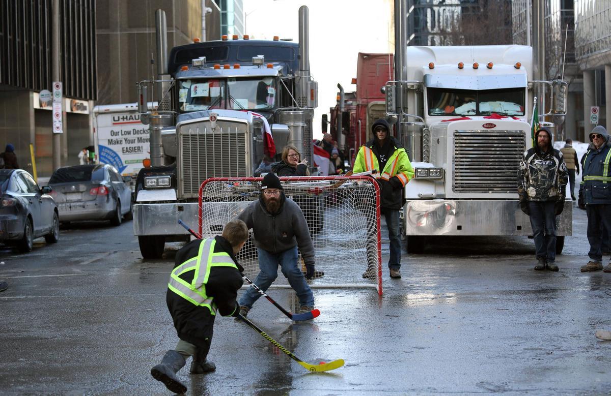 Protesters and supporters play street hockey as demonstrators continue to protest the vaccine mandates implemented by Prime Minister Justin Trudeau on February 7, 2022 in Ottawa, Canada. - Canadian authorities struggled Monday to tackle a truckers protest against Covid restrictions which has paralyzed the national capital for days and threatens to snowball into a full-blown political crisis for Prime Minister Justin Trudeau. (Photo by Dave Chan / AFP)