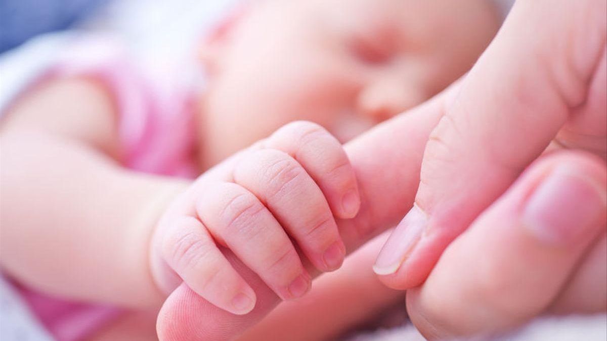 Bebé recién nacido agarra la mano de su madre.