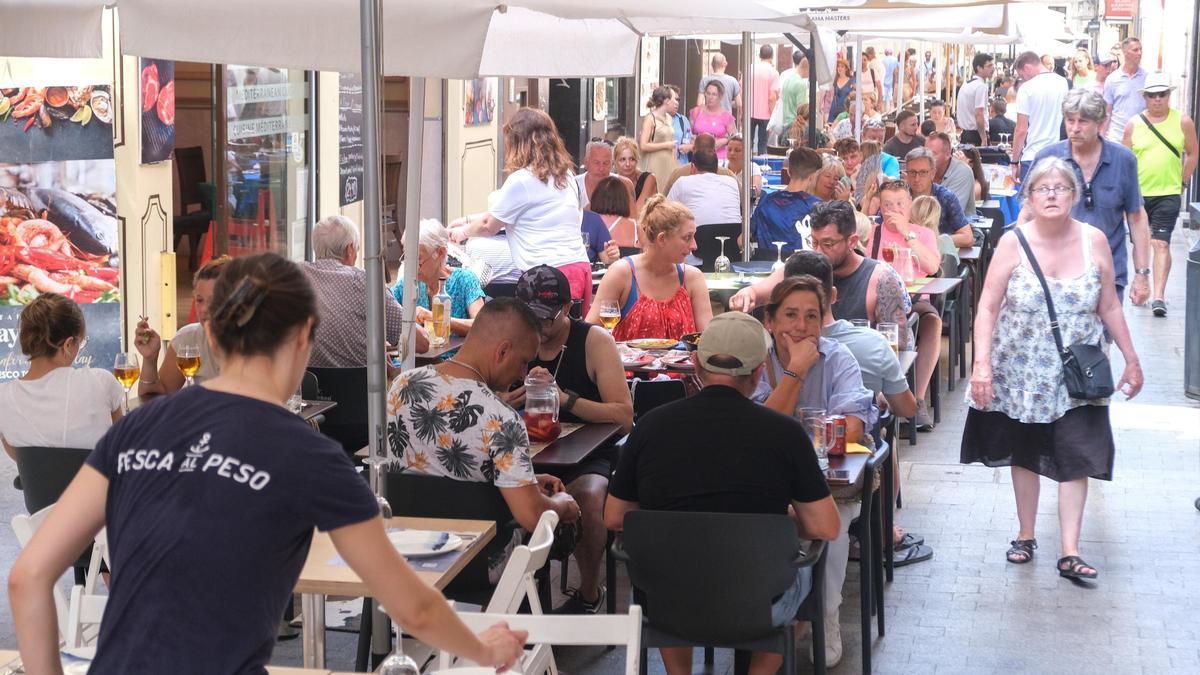 Una camarera atiende las mesas de una terraza en Alicante.