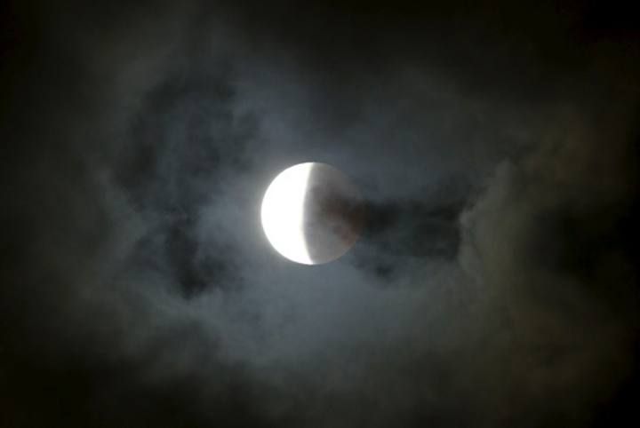 Clouds pass over as the moon is partially covered by the Earth's shadow during a total lunar eclipse in Cape Town