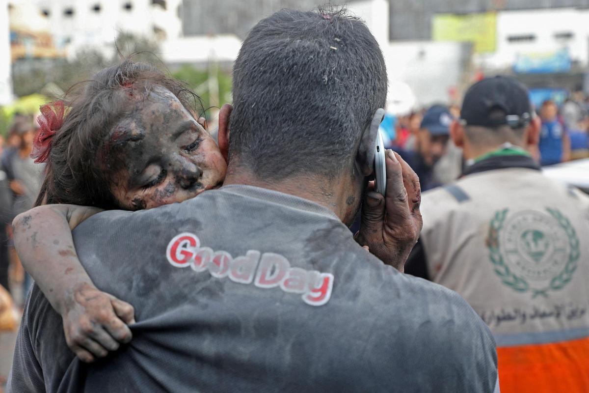 Un palestino cubierto de polvo traslada a una niña herida al hospital Al-Shifa, en la ciudad de Gaza