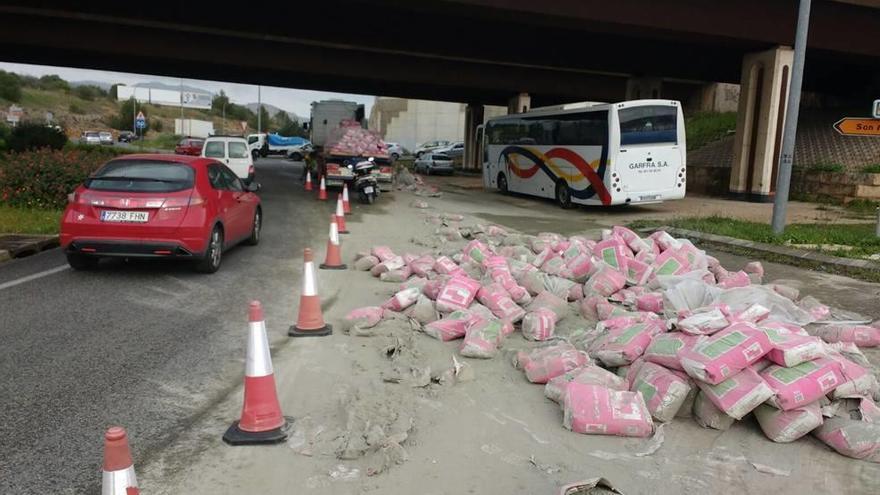 Varios coches circulan junto a los sacos de cemento que perdió el camión, ayer en la rotonda de la salida hacia Puigpunyent.