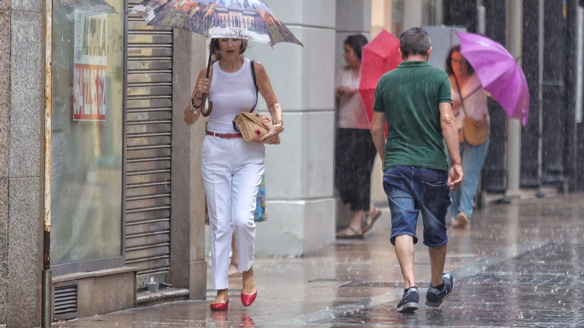 Vecinos de Castelló se protegen de la lluvia este pasado miércoles.