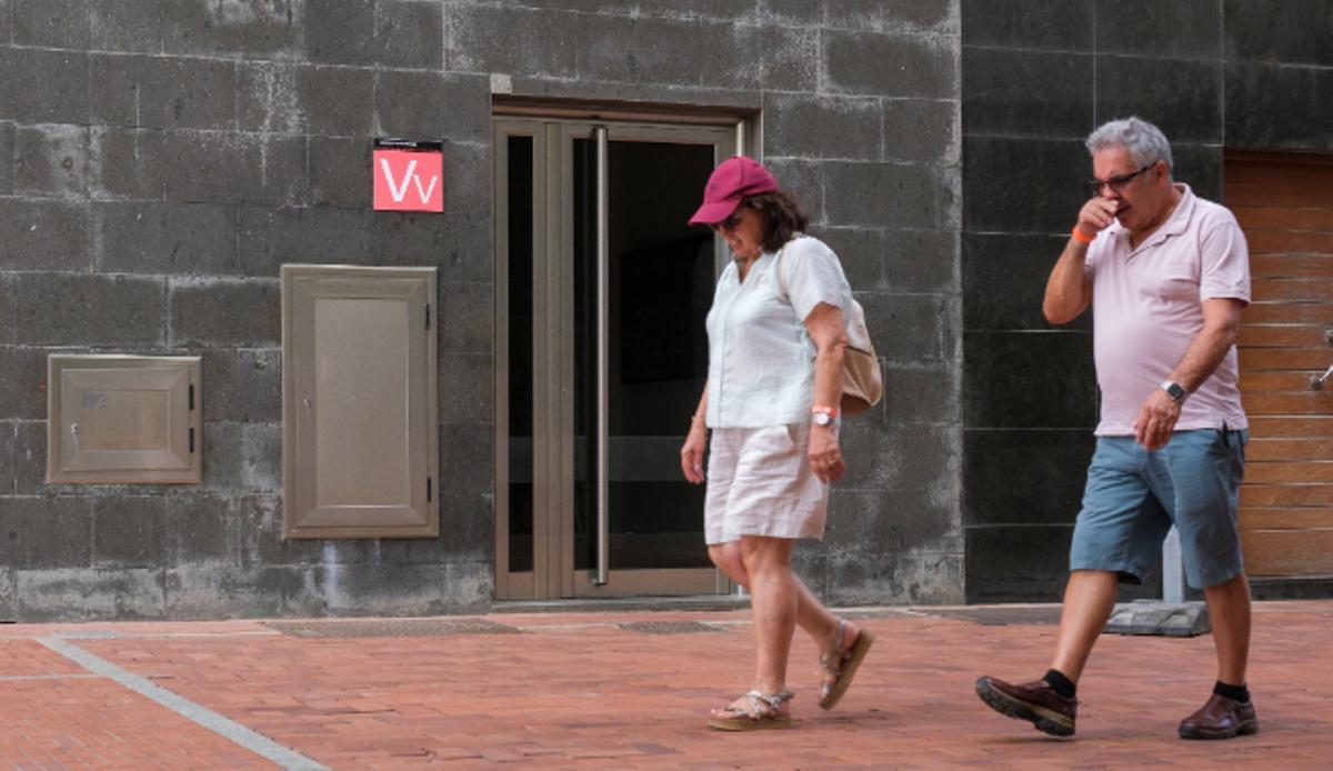 Dos ciudadanos pasan junto a un edificio de pisos turísticos en la capital grancanaria.