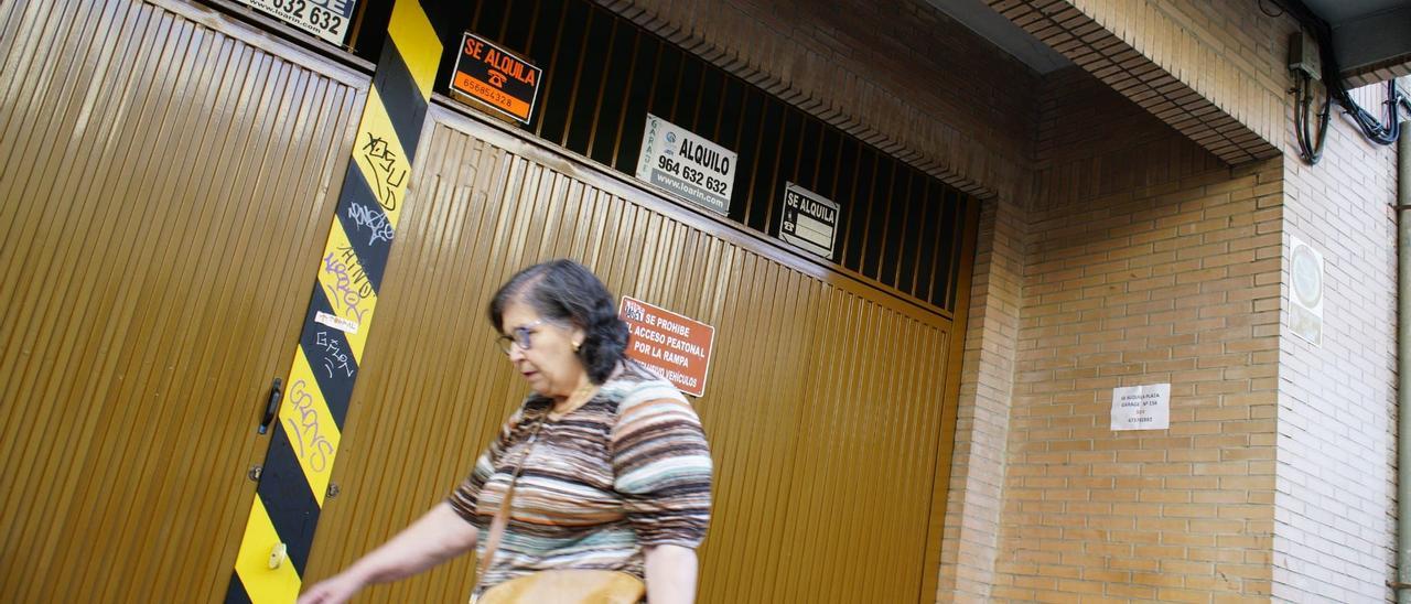 Una entrada a un párking subterráneo de un bloque de viviendas en Castellón, con carteles de ‘Se alquila’ y ‘Se vende’ plaza de garaje.