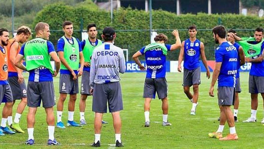 Los futbolistas del Deportivo rodean a Fernando Vázquez sobre el césped de Abegondo.