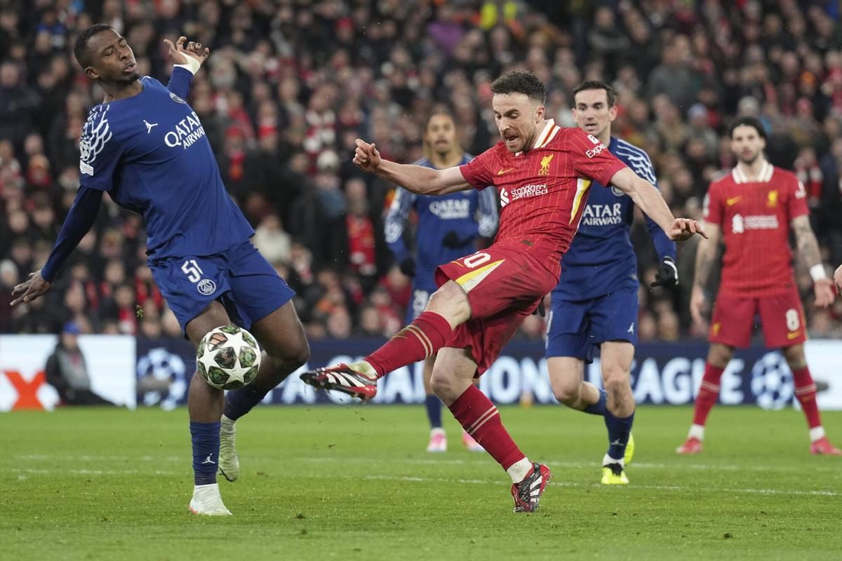 Liverpool's Diogo Jota shoots by PSG's Willian Pacho during the Champions League round of 16 second leg soccer match between Liverpool and Paris Saint-Germain at Anfield in Liverpool, England, Tuesday, March 11, 2025. (AP Photo/Jon Super)