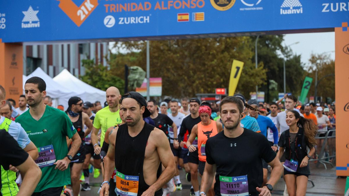 Corredores en la última media maratón de València pasan bajo el arco de salida con el patrocinio de Luanvi.