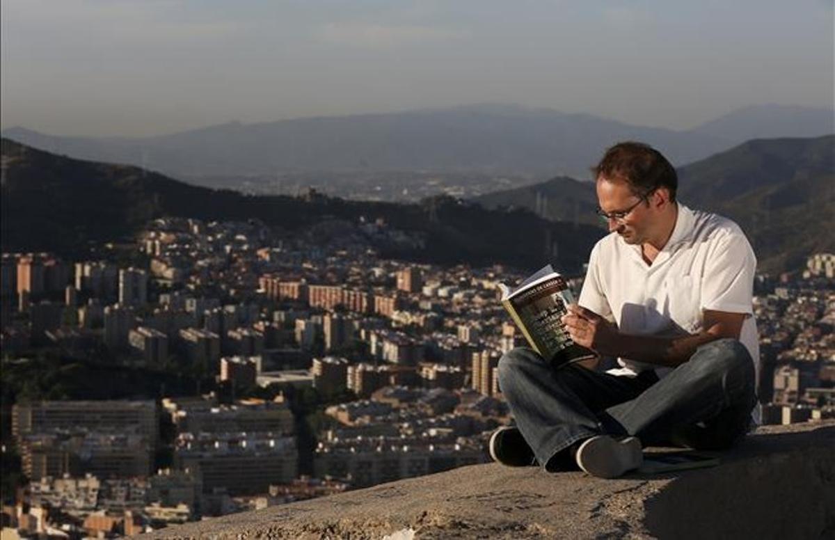 El líder d’ICV, Joan Herrera, fulleja ’Els barris de Barcelona’, de Josep Maria Huertas Claveria, assegut al mirador del Turó de la Rovira, amb Torre Baró al fons. JULIO CARBÓ El líder d’ICV, Joan Herrera, fulleja ’Els barris de Barcelona’, de Josep Maria Huertas Claveria, assegut al mirador del Turó de la Rovira, amb Torre Baró al fons. JULIO CARBÓ