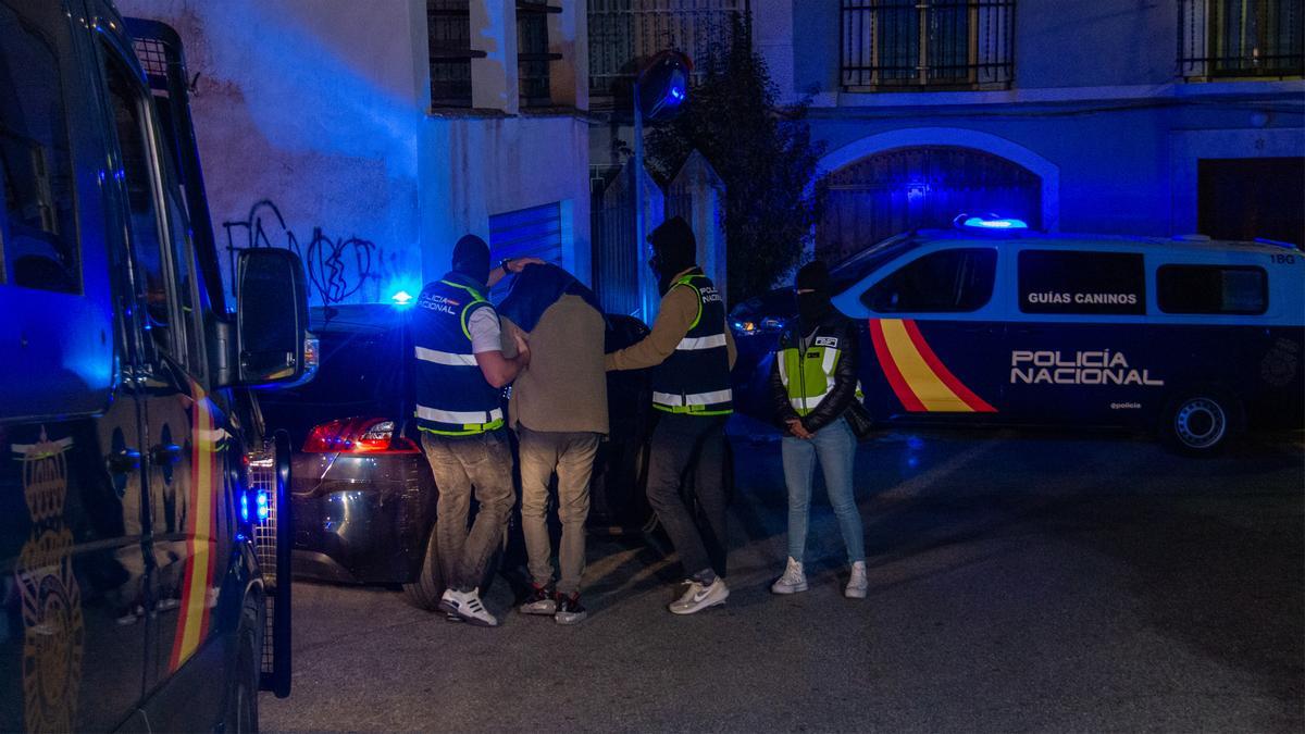 Efectivos de la Policía Nacional registran una vivienda del centro de Lanjarón (Granada) junto a uno de los dos detenidos en este municipio.
