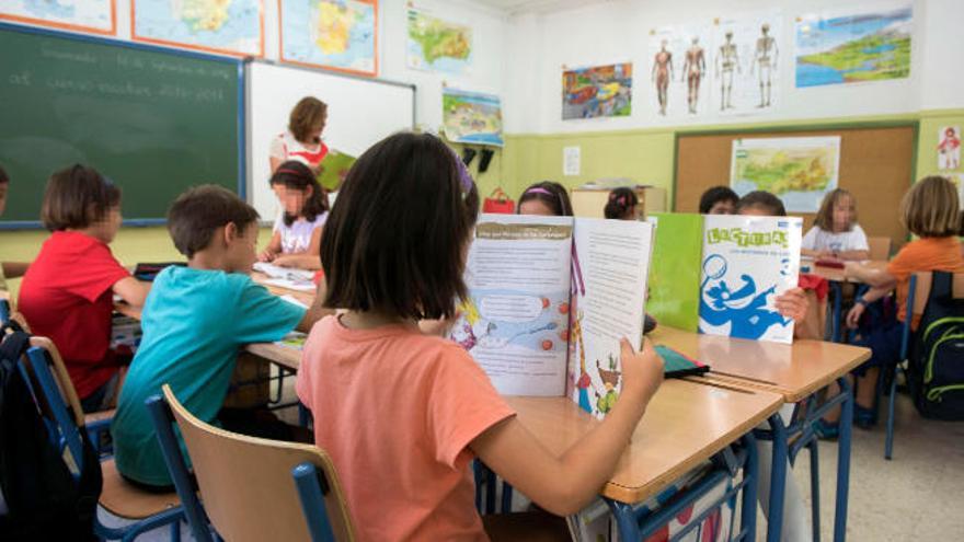 Una niña lee junto a sus compañeros y su profesora durante su clase de Lengua en Primaria.