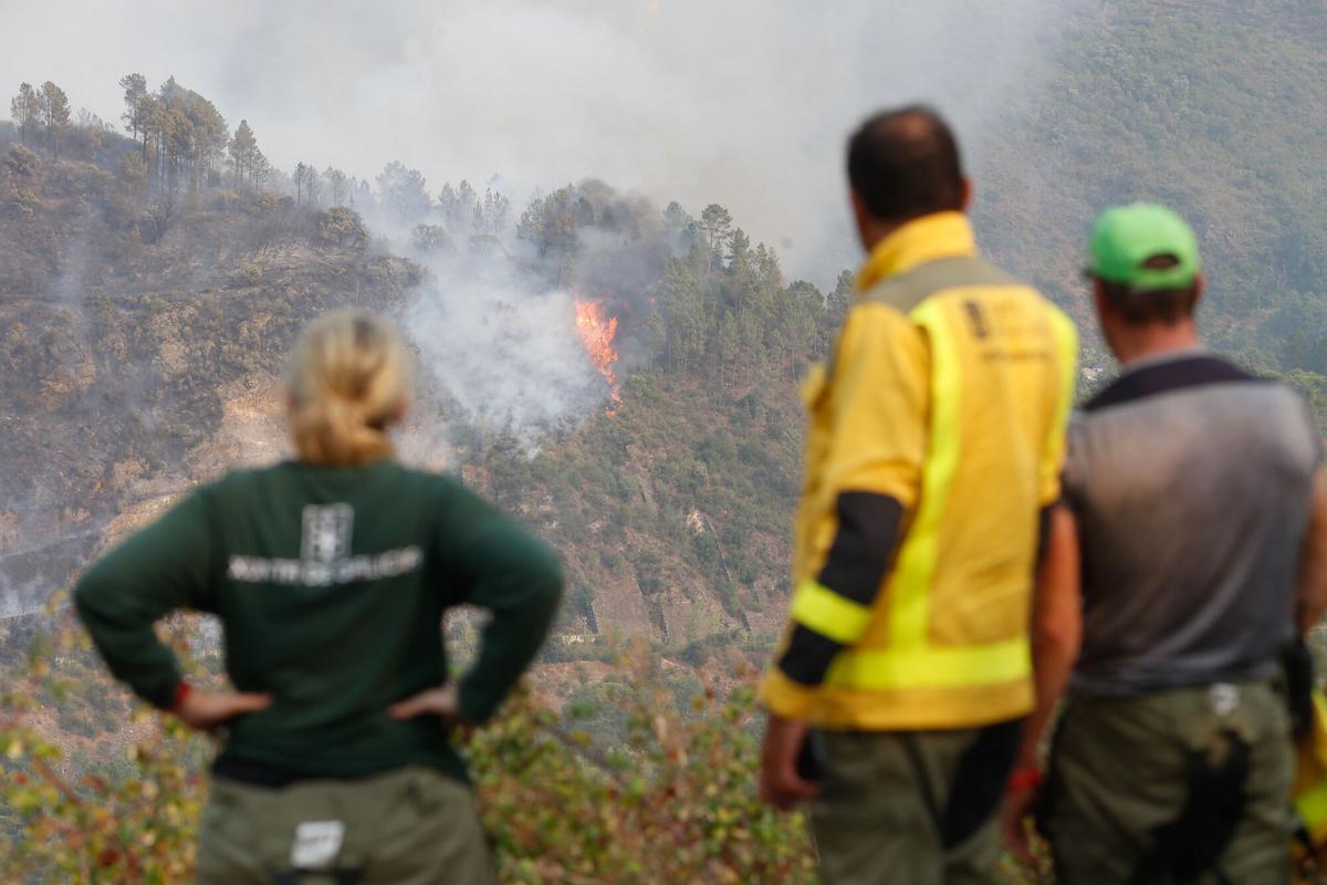 Varias personas observan el fuego, a 17 de agosto de 2025, en Quiroga, Lugo, Galicia (España). El incendio registrado en Larouco (Ourense) “se comportó de un modo explosivo” y pasó el Sil hasta por 15 puntos, para acabar entrando en la provincia de Lugo, al cruzar a Quiroga. La calidad del aire en Ourense y Lugo continúa viéndose afectada por los efectos de los incendios forestales en la provincia, donde aún hay 13 fuegos sin extinguir, 12 activos y 1 estabilizado, que ya han calcinado alrededor de 50.570 hectáreas.