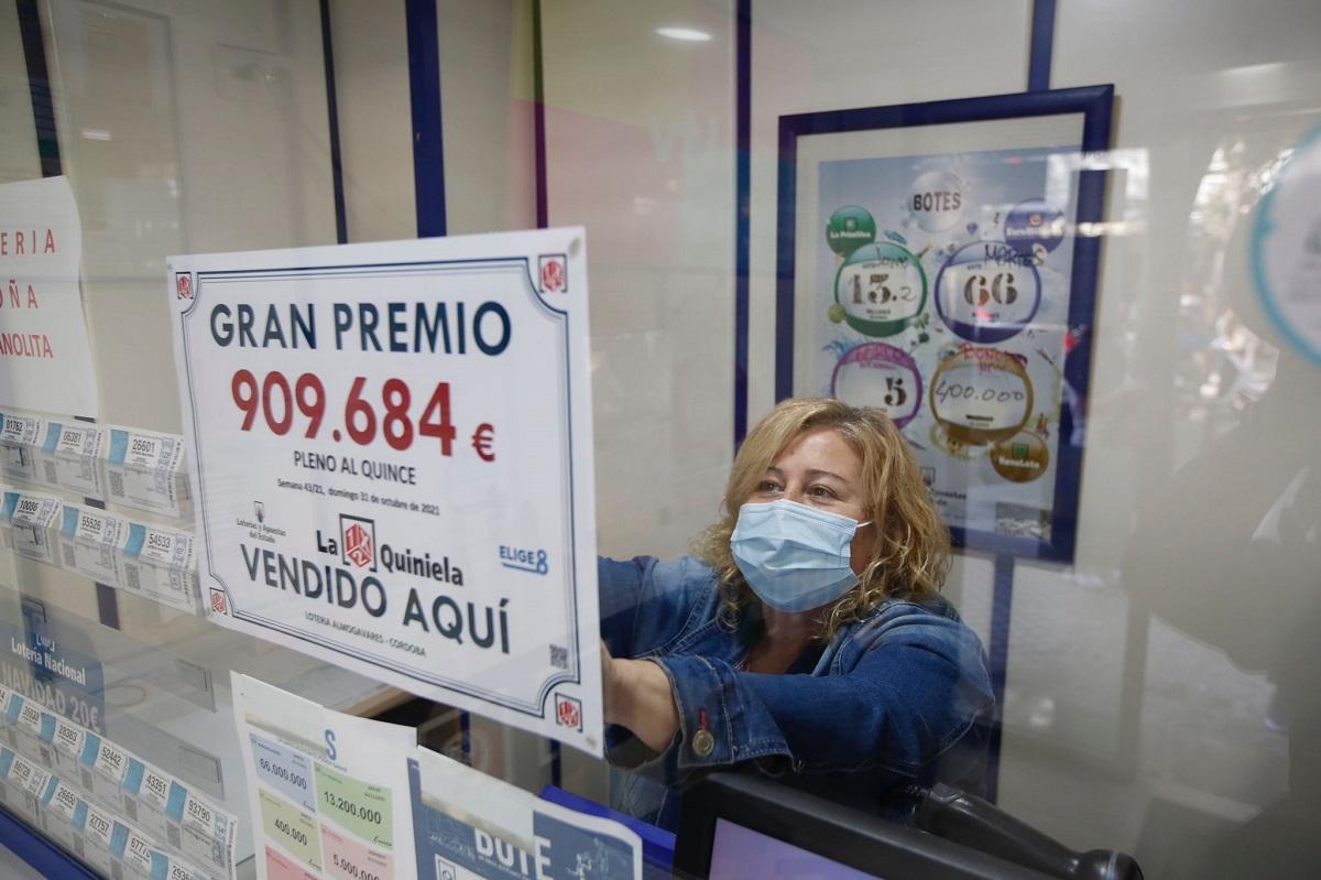 Una de las dependientas del despacho de apuestas coloca un cartel donde se informa del premio.