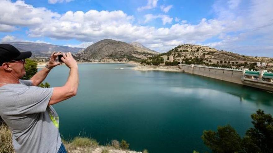 Un ciudadano toma una foto del embalse del Amadorio en una imagen reciente.