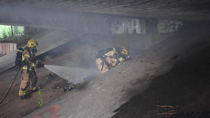 Los bomberos, entre el humo, apagan las llamas.