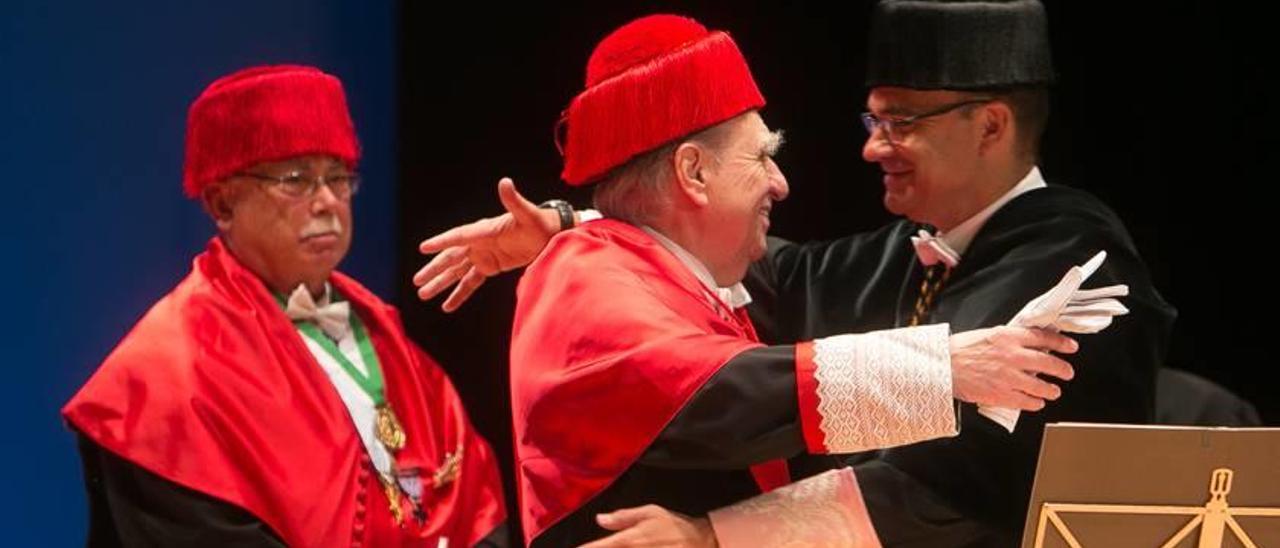 El rector, Manuel Palomar, abraza al nuevo doctor Honoris Causa por la UA, Julio María Sanguinetti, ante la mirada del padrino, el catedrático José Manuel Canales.