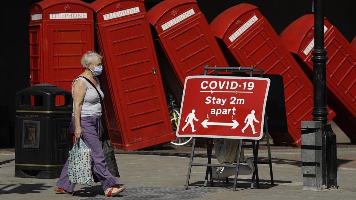 Una mujer pasa por un cartel en el que se exige a los londinenses que mantengan la distancia de seguridad, el 22 de junio del 2020