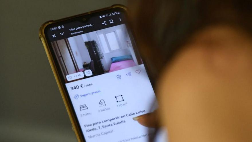 Una joven observa anuncios de alquiler de pisos con su teléfono.