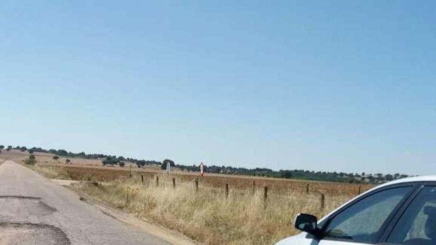 Un coche esquiva los baches del camino rural a Almendra.