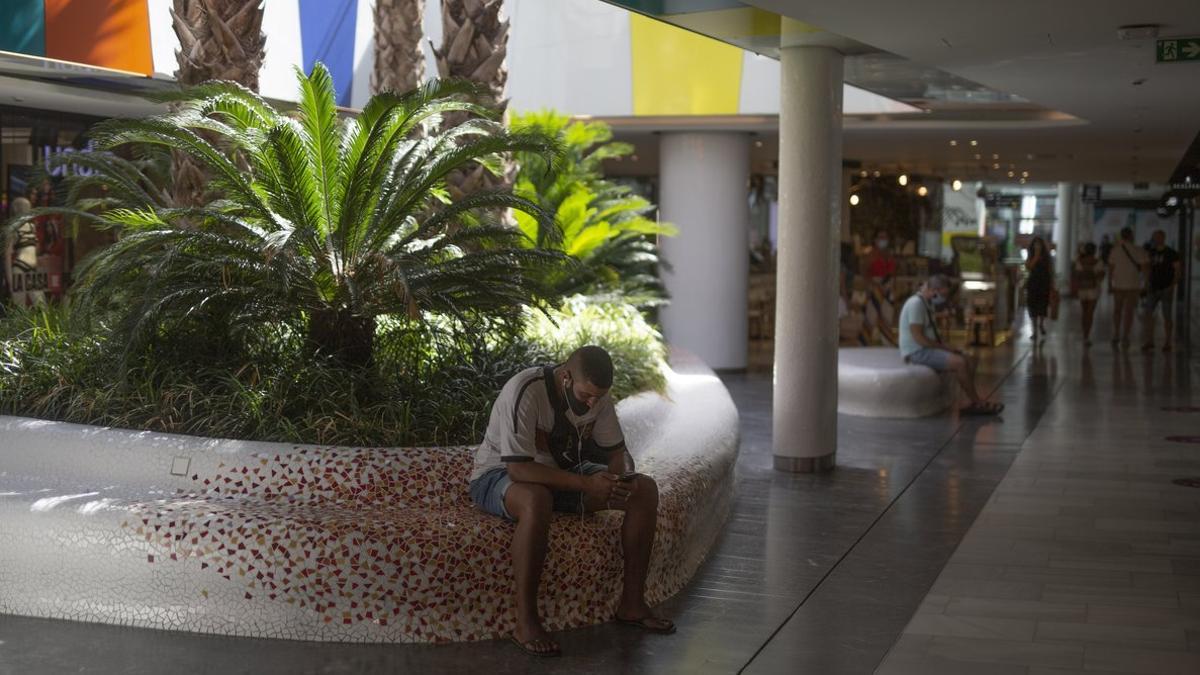 Gente sentada en los bancos del centro comercial Glòries