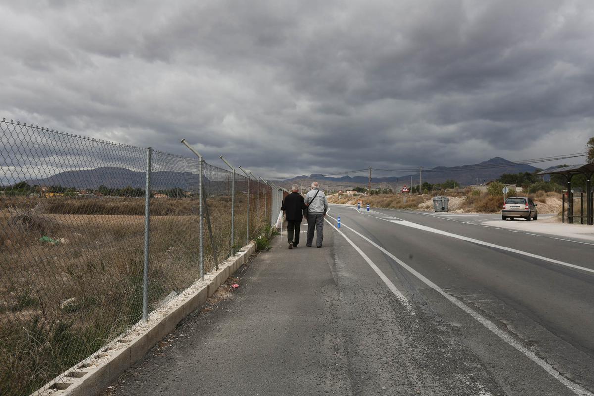 Dos ancianos caminan junto a una carretera en la Cañada.
