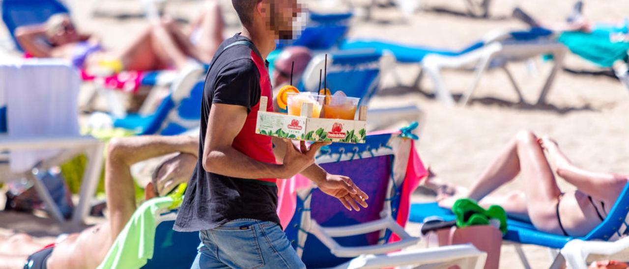 Uno de los «mojiteros» con una bandeja de bebida en una de las playas de Benidorm. DAVID REVENGA