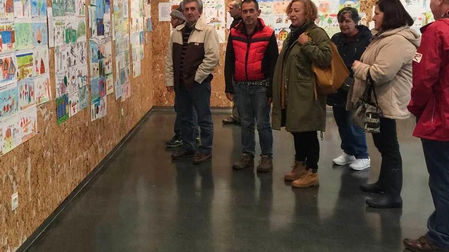 Visitantes a la exposición de carteles del Certamen de la castaña en la Casa de Cultura de Arriondas, ayer.