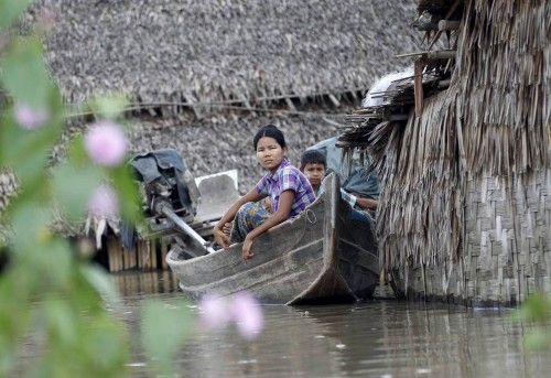 People sit on a boat near their home in a flooded village outside Zalun Township, Irrawaddy Delta