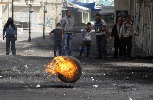 Un neumático en llamas pasa rodando delante de disidentes palestinos