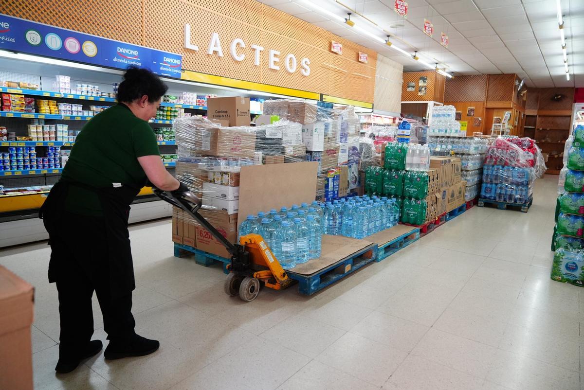 Una trabajadora coloca palés de agua en un supermercado de Pozoblanco.