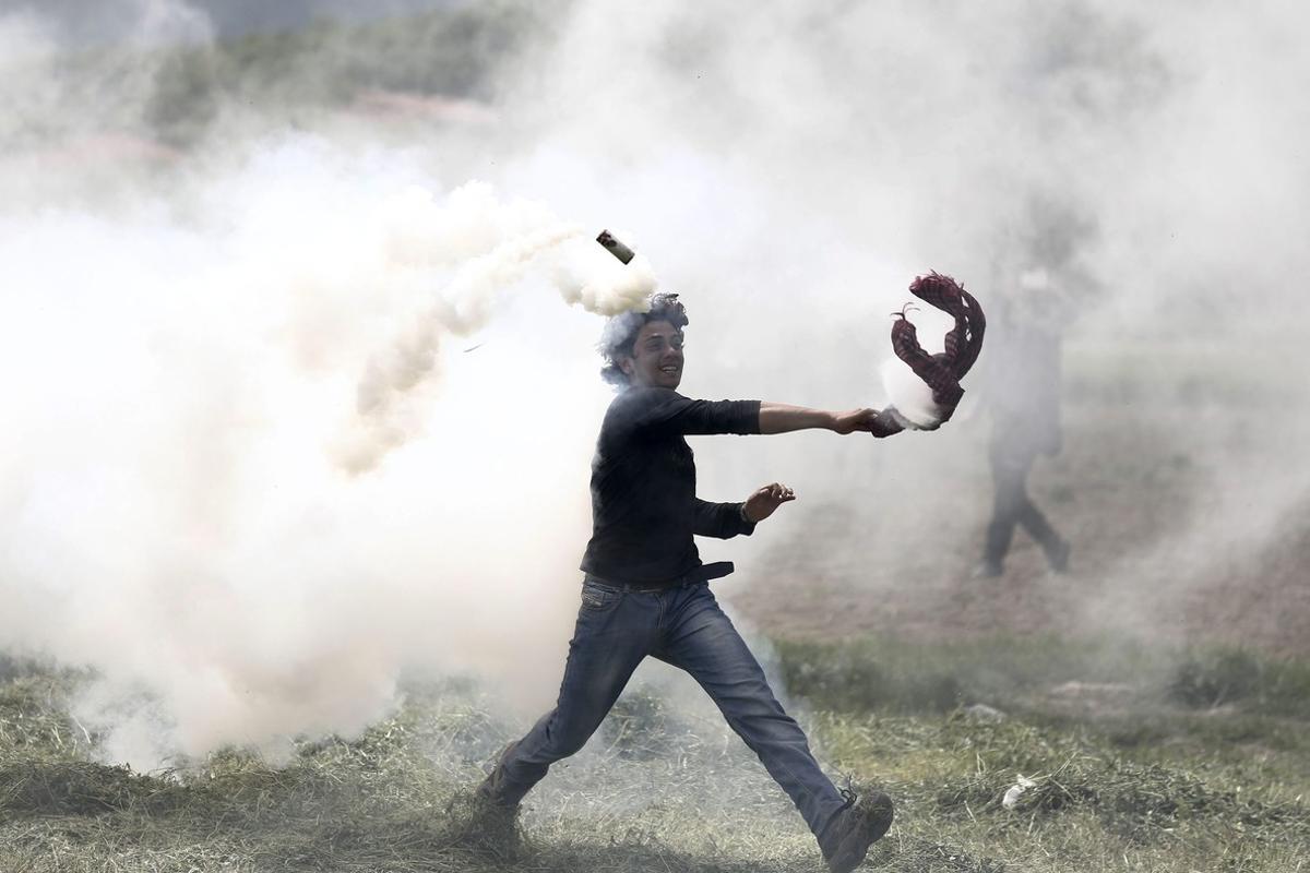 TSI04 IDOMENI (GRECIA) 13/04/2016.- Un refugiado lanza de vuelta un bote de gas lacrimógeno durante una protesta en el campo de refugiados de Idomeni, situado en la frontera entre Macedonia y Grecia, hoy, 13 de abril de 2016. Las fuerzas antidisturbios de la Antigua República Yugoslava de Macedonia (ARYM) reprimieron hoy nuevamente con gases lacrimógenos y granadas aturdidoras el intento de un grupo de refugiados de cruzar ilegalmente la frontera desde Idomeni. EFE/Kostas Tsironis