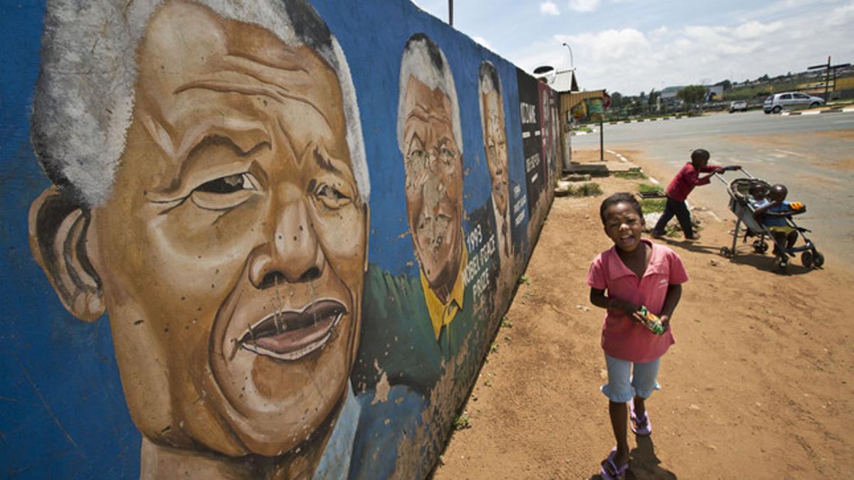 Unos niños corren junto a un mural dedicado a Mandela, esta sábado en el barrio de Soweto, en Johannesburgo.