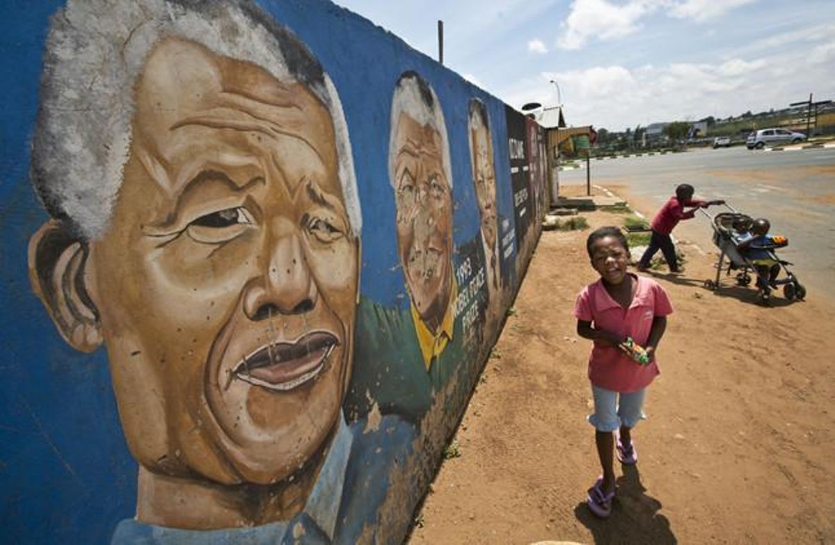 Uns nens corren al costat d’un mural dedicat a Mandela, aquesta dissabte al barri de Soweto, a Johannesburg.