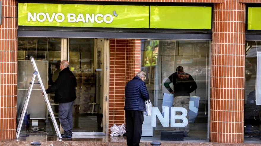 Varios operarios trabajan para desmontar la sucursal de Novo Banco en Alicante, ayer.