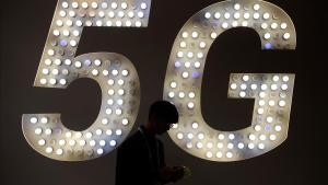 Un visitante usa su teléfono junto a un cartel de 5G.