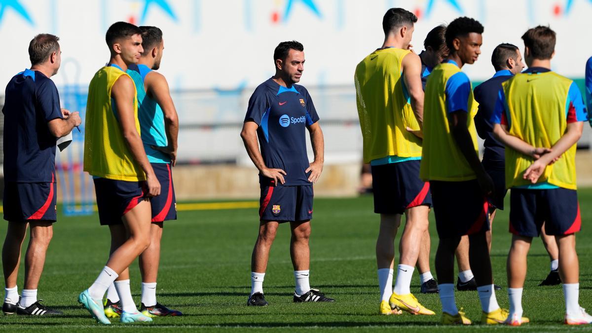 Entrenamiento del FC Barcelona Xavi espera la llegada de todos los jugadores para repartir instrucciones.