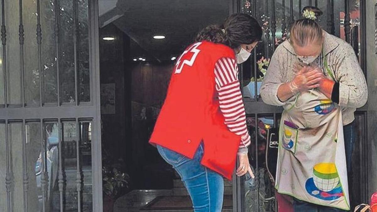 Una voluntaria de Cruz Roja lleva comida a una señora mayor que vive sola.