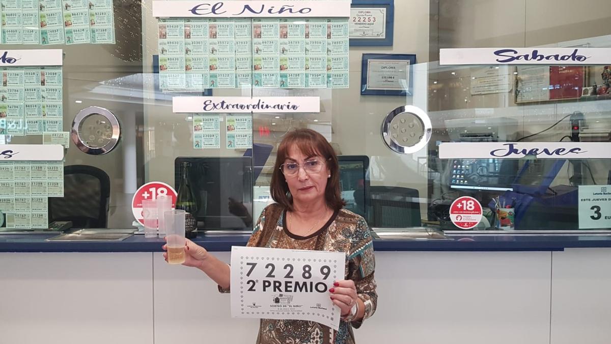 Saro Martín, con el cartel del Segundo Premio de la Lotería del Niño, en la administración del Centro Comercial Deiland, en Playa Honda