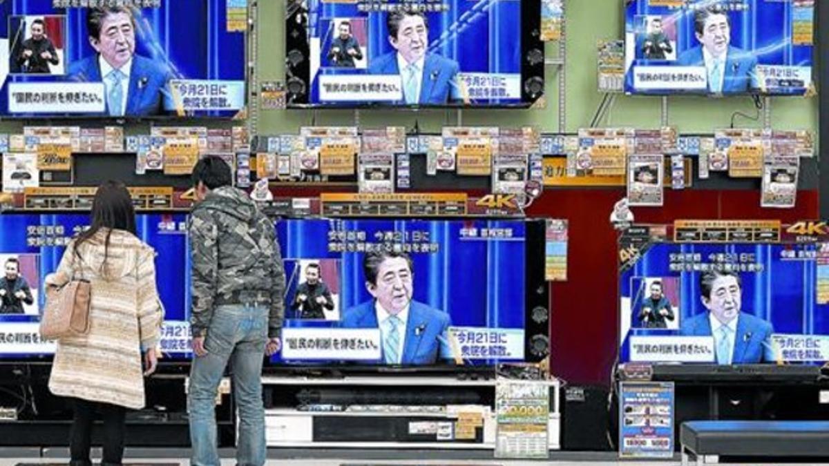 Una pareja mira en la televisión una rueda de prensa del primer ministro, Shinzo Abe, ayer, en Osaka.