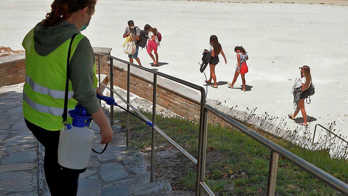 Una mujer desinfecta una de las barandillas de la playa de O Vicedo, en Lugo.