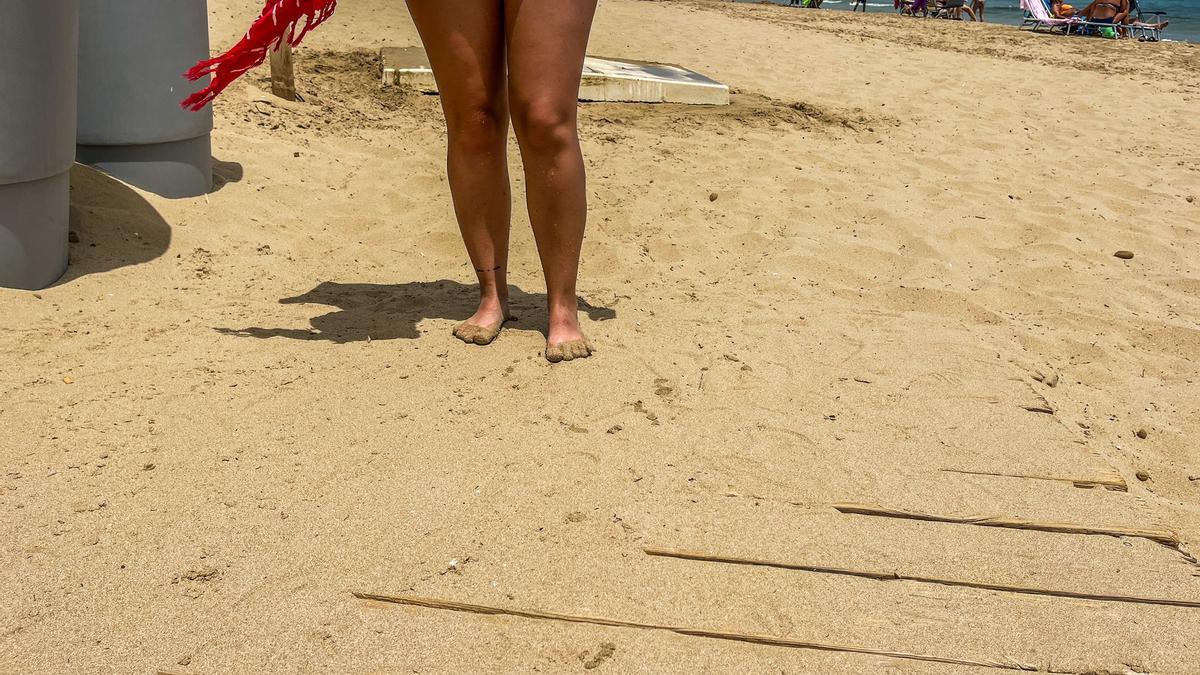 Una bañista con los pies llenos de arena tras asearse en el lavapiés, al no estar cerca la pasarela de madera